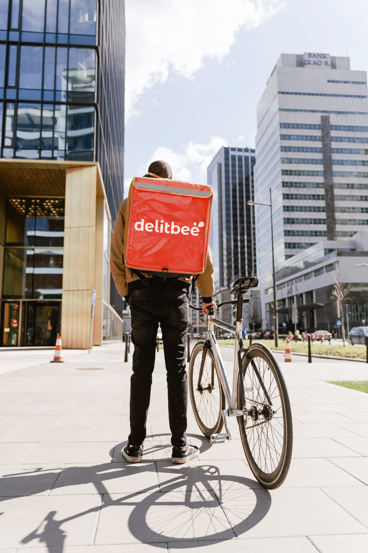 Repartidor de comida a domicilio de espaldas con una mochila isotermica con el logo de Delitbee