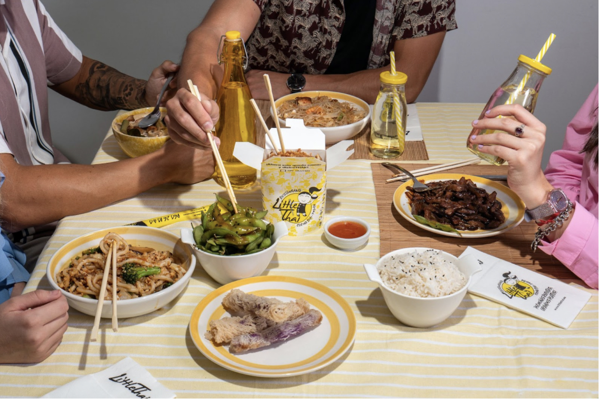 Gente comiendo en casa comida del restaurante tailandés Little Thai a domicilio